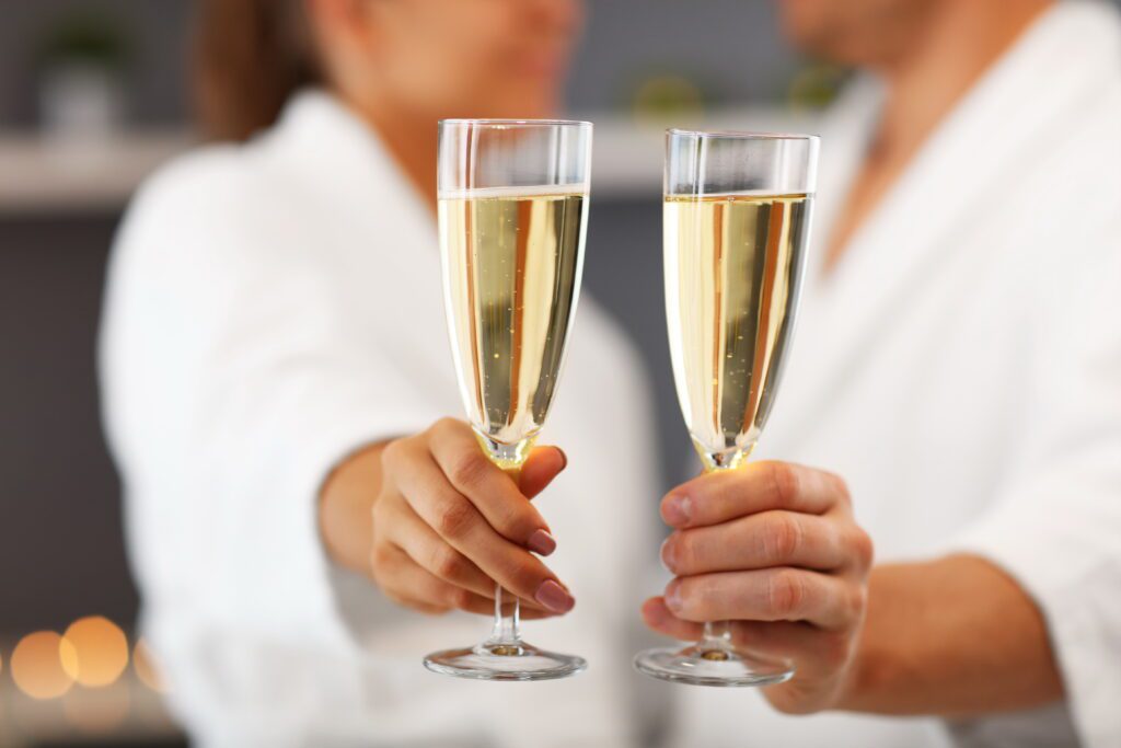 couple in robes with prosecco glasses