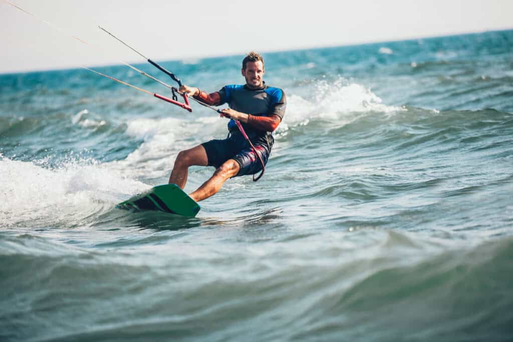 Kite surfer riding the waves at Old Thorns golf and leisure resort, enjoying water sports and outdoo.