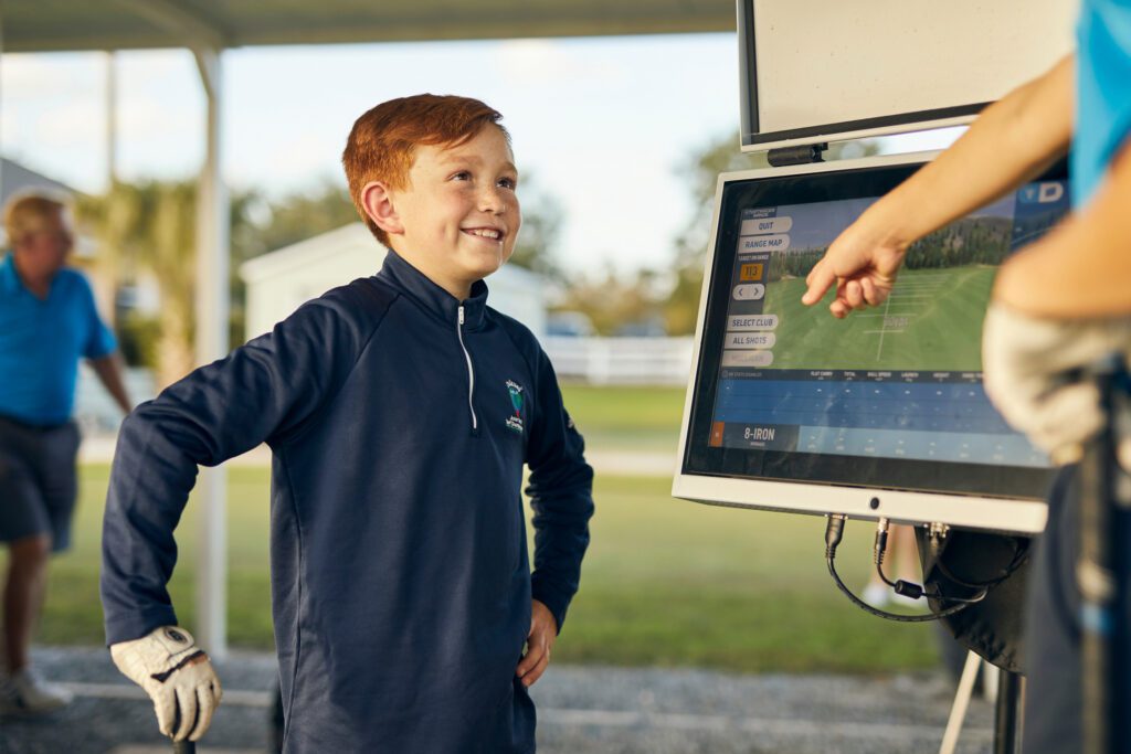 Young boy enjoying Toptracer driving range at Old Thorns Hotel & Resort.