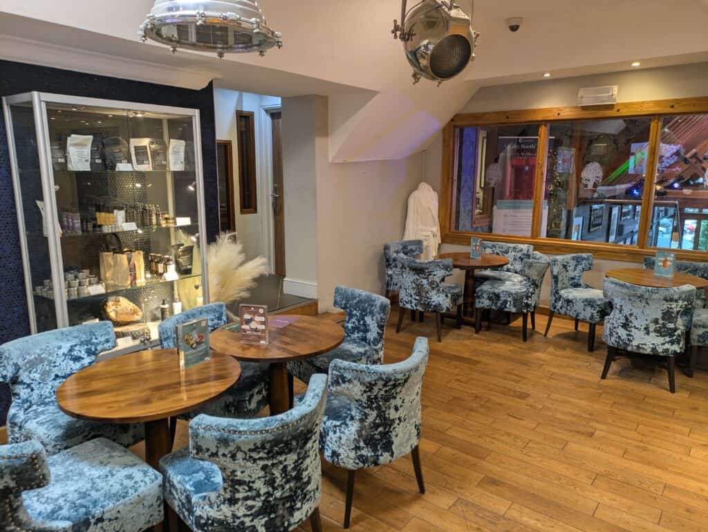 Old Thorns lounge with plush blue velvet chairs and wooden tables.