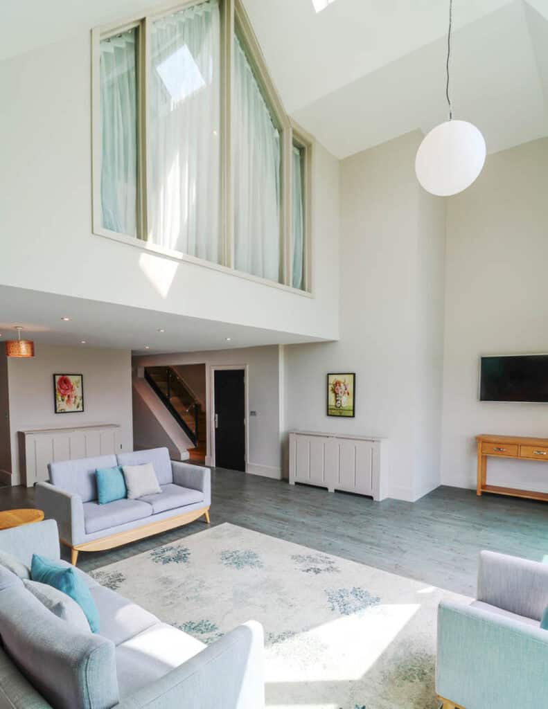 Modern living room with high ceilings, large windows, and stylish furniture at Old Thorns.