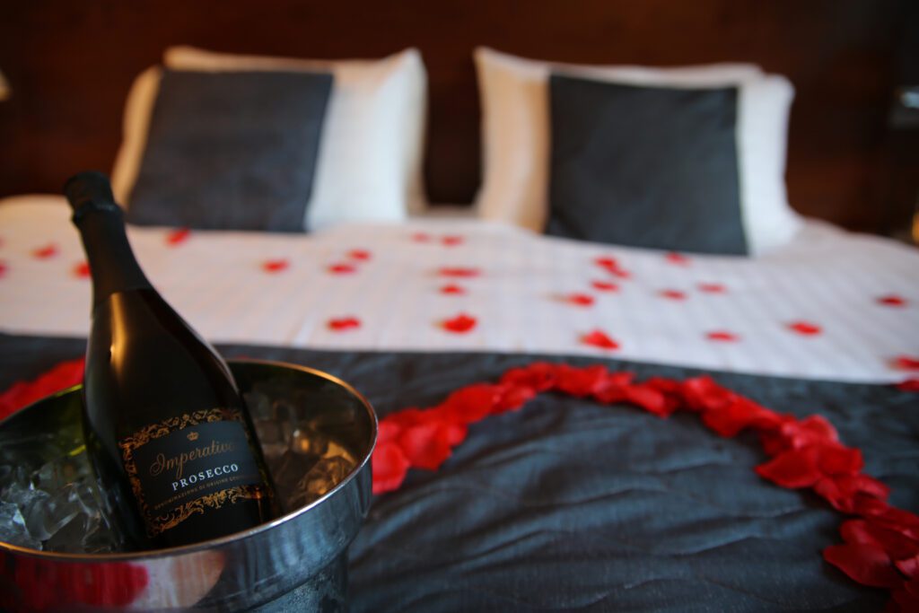 Prosecco and rose petals on a bed for a romantic stay