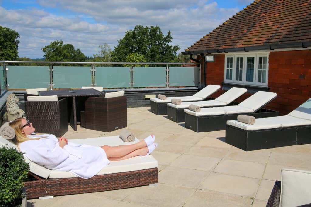Relaxing rooftop terrace at Old Thorns with sun loungers and panoramic countryside views.