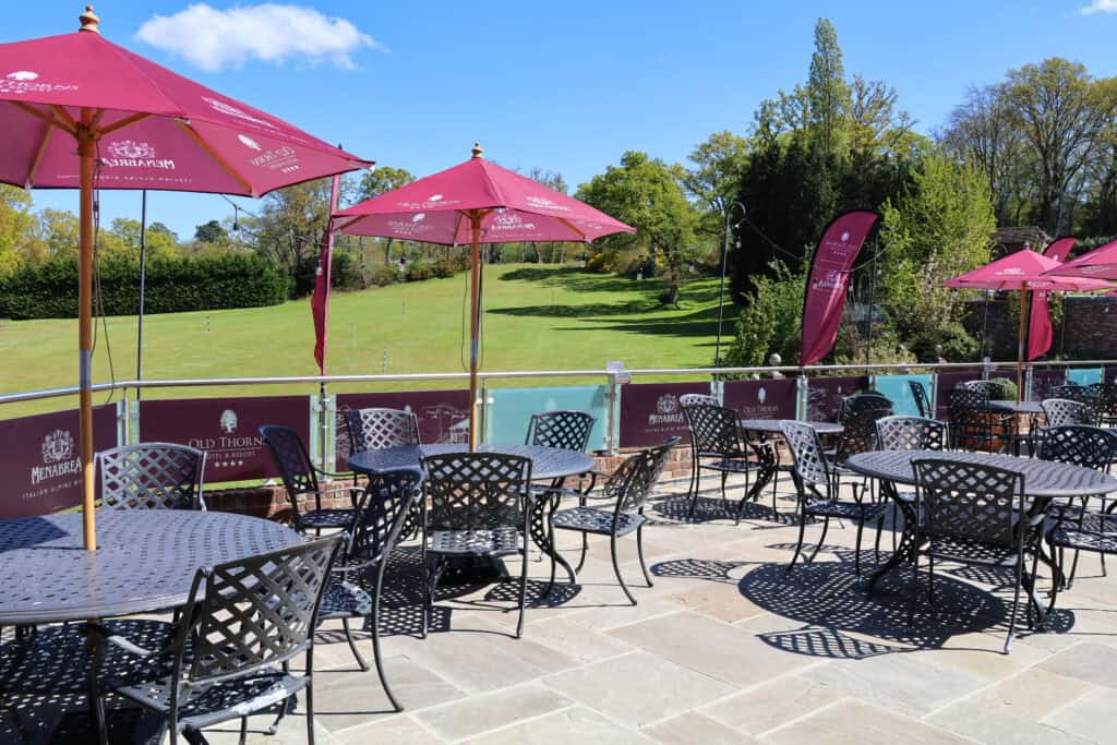 Outdoor terrace with seating and pink umbrellas at Old Thorns Golf & Spa. Perfect for relaxing with.