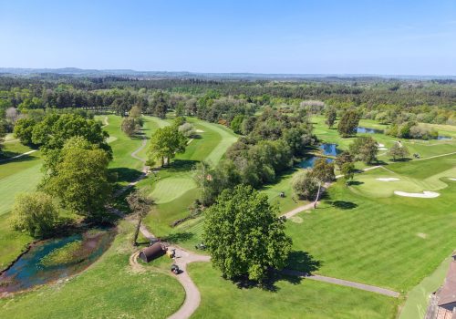 Aerial photo of the golf course with fairways, greens and woodlands