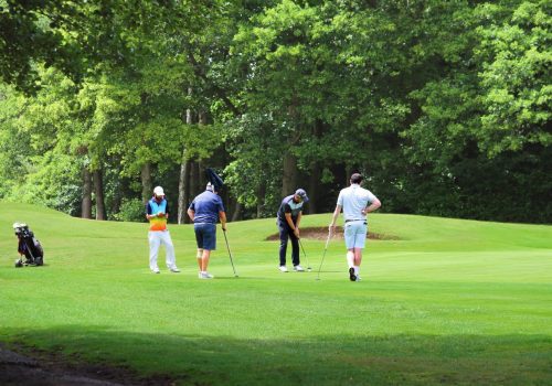Four golfers around the pin putting