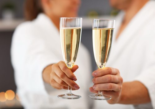 couple in robes with prosecco glasses